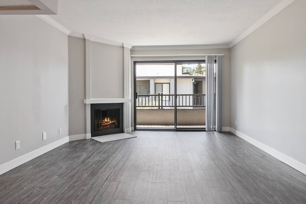 an empty living room with a fireplace and a balcony