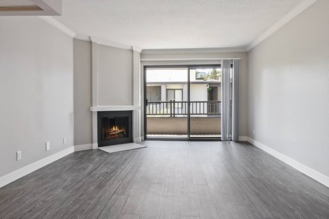 an empty living room with a fireplace and a balcony