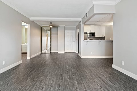 an empty living room and kitchen with wood flooring
