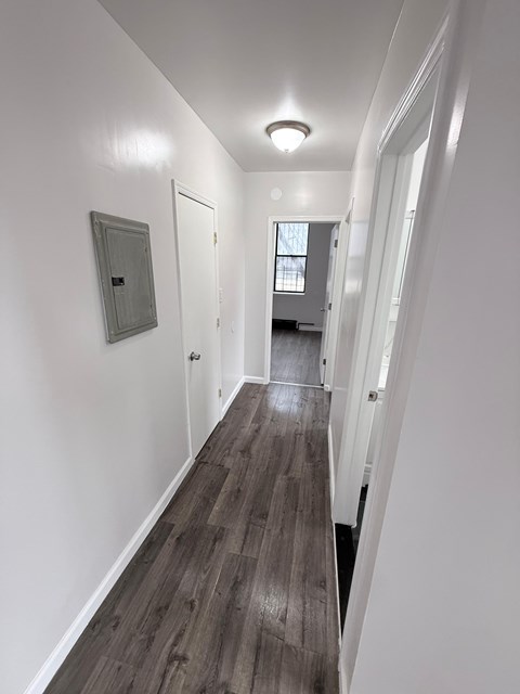 A long hallway with white walls and wood flooring.