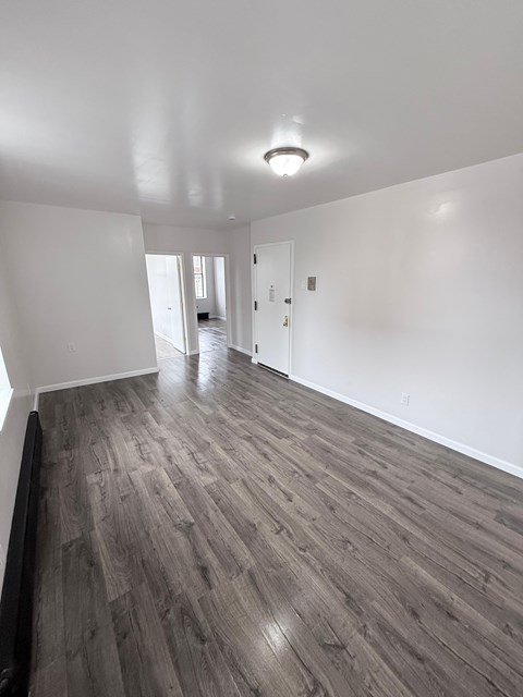 A room with wooden flooring and white walls.