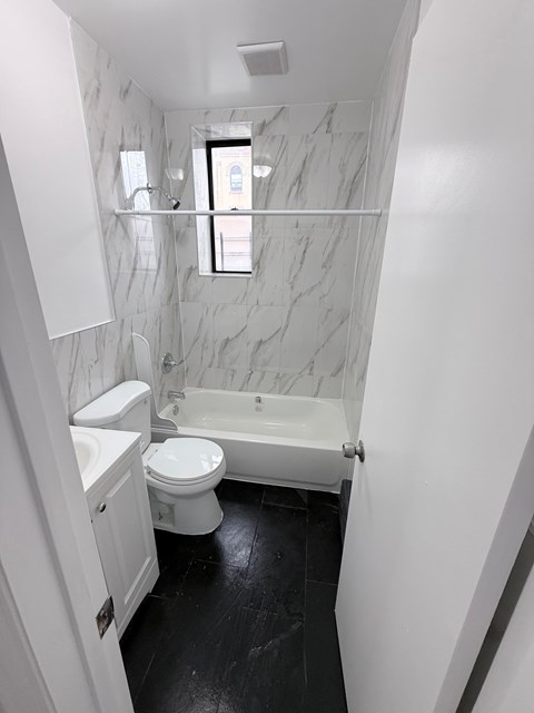 A white toilet and sink in a bathroom with marble walls.