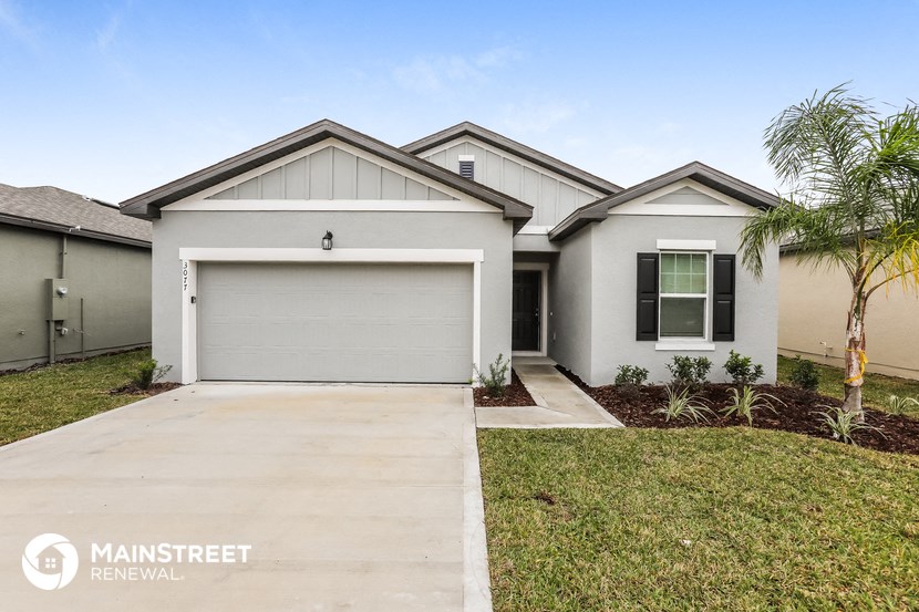 a white house with a garage and a palm tree