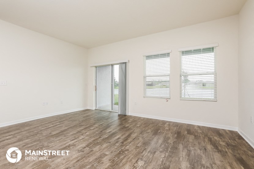 an empty living room with wood flooring and a sliding glass door