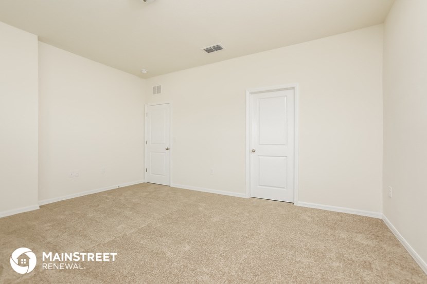 the living room of a home with white walls and carpet