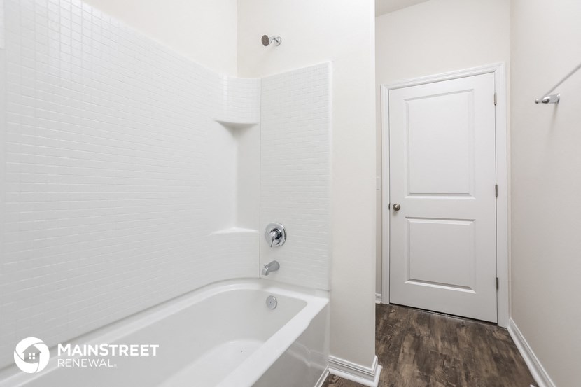 a white bathroom with a tub and a white door