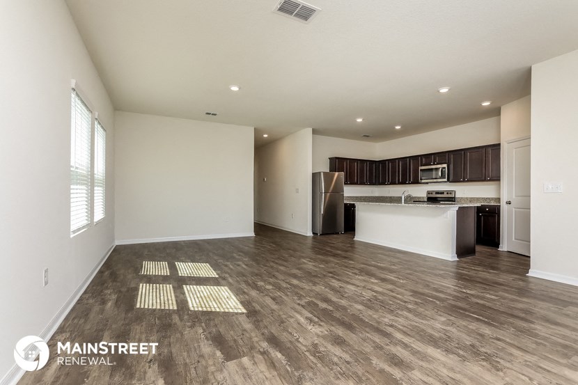 the living room and kitchen of an apartment with wood flooring