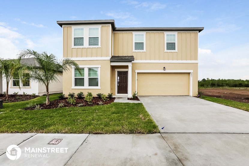 a beige house with a driveway and a palm tree