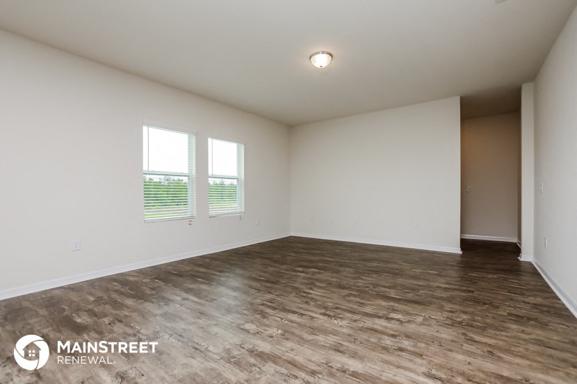 an empty living room with wood flooring and white walls