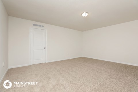 the living room of a home with carpet and a white door