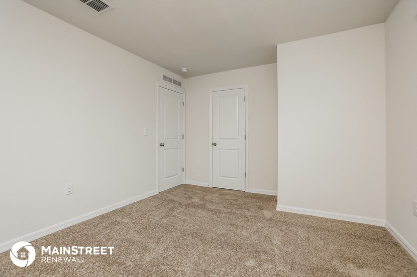 a bedroom with white walls and carpet and two doors