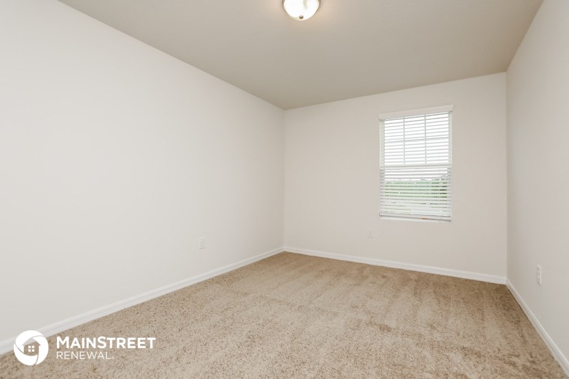 the spacious living room with carpeting and a window