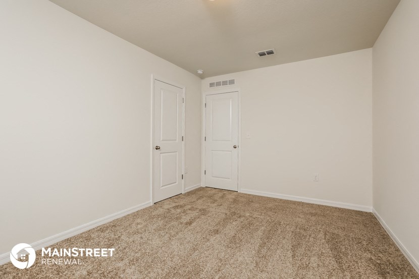 the spacious living room of a home with white walls and carpet