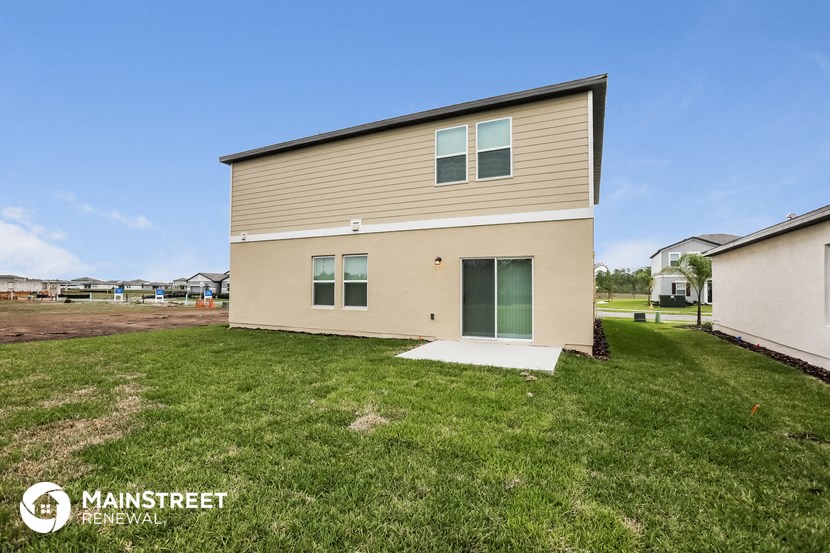 the exterior of a tan house with a yard and grass