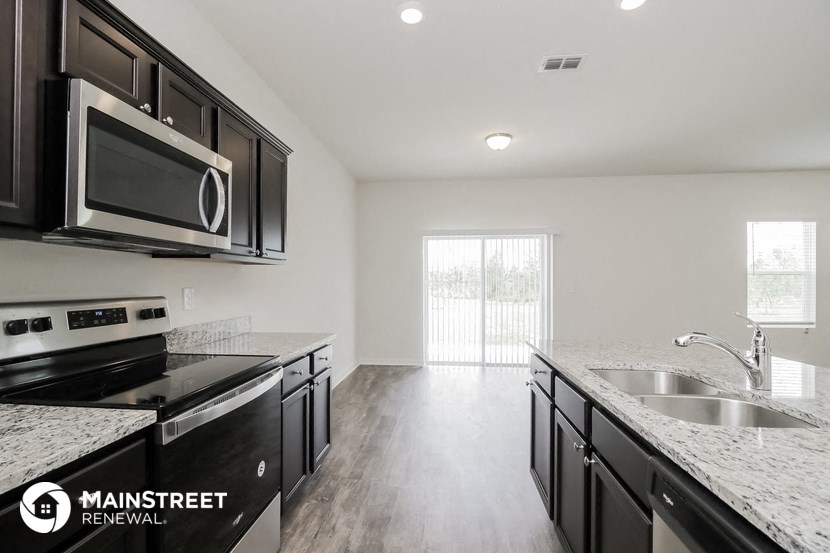 the kitchen of an apartment with black cabinets and granite counter tops