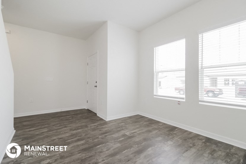 the living room of an apartment with wood floors and white walls