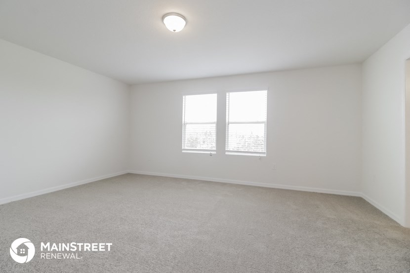 the interior of an empty room with two windows