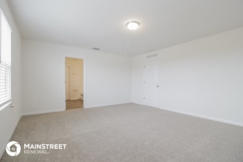 the living room of an apartment with white walls and carpet