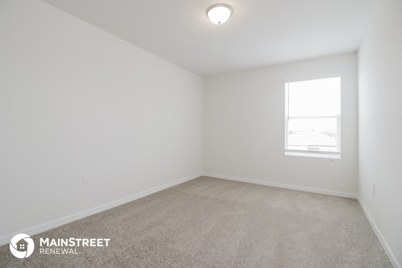 the living room of an apartment with carpet and a window