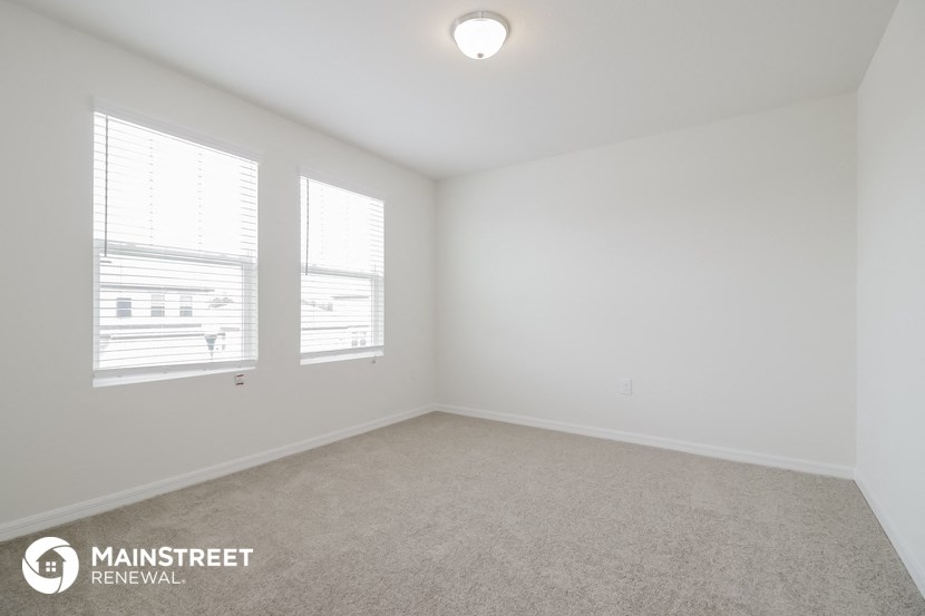 a bedroom with three windows and a carpeted floor