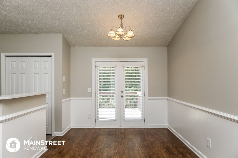 the living room of a house with white doors and a wooden floor