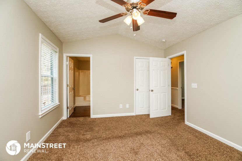 a living room with carpet and a ceiling fan