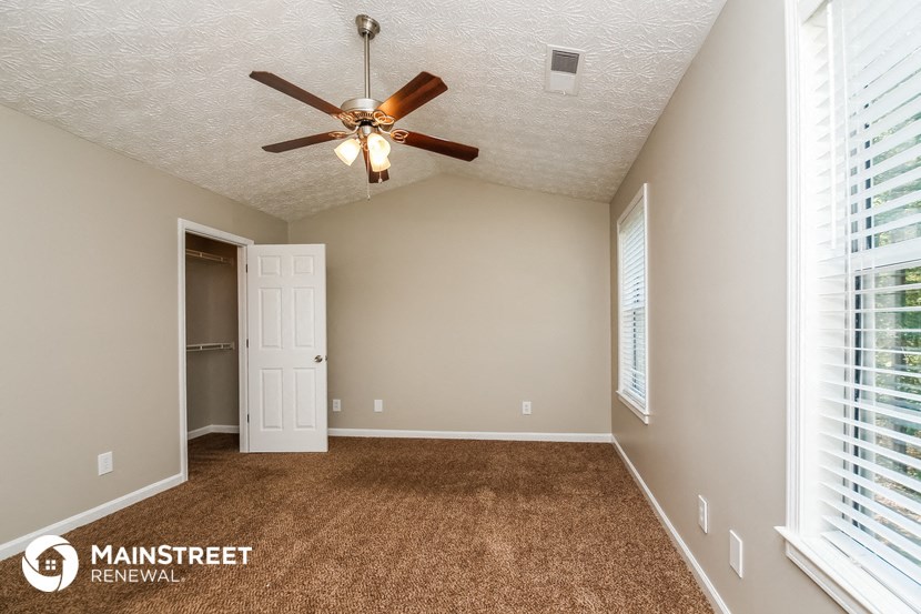 the master bedroom has a ceiling fan and a door to the closet