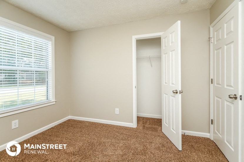 the master bedroom has carpeted floors and a walk in closet