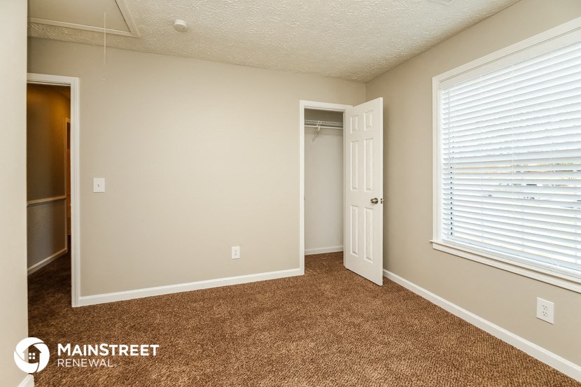 the spacious living room has carpeted floors and a large window