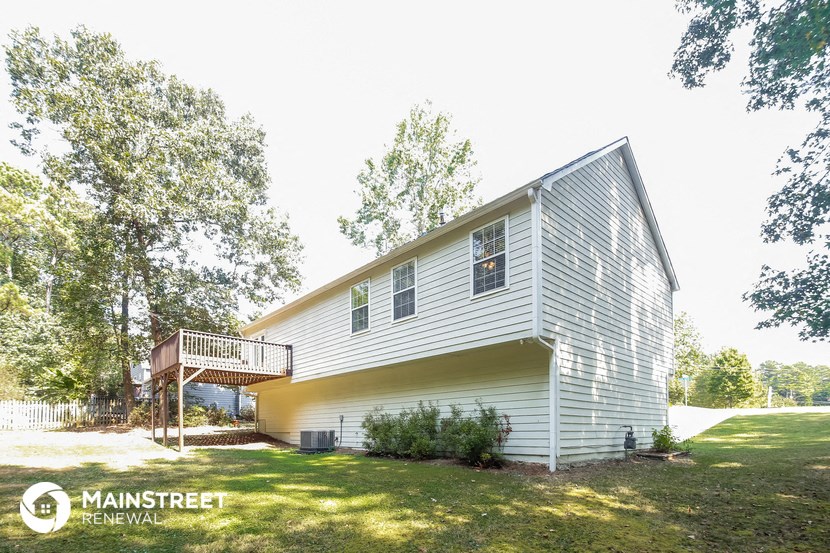 a white house with a deck on a lawn