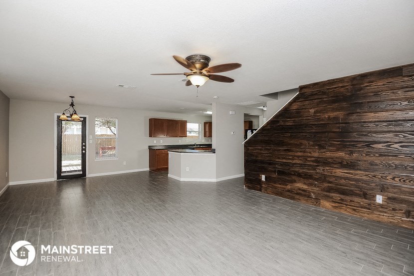 a large living room with a wooden wall and a ceiling fan