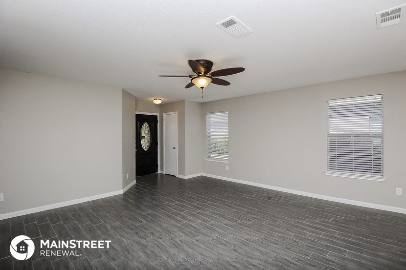 the living room is spacious and has a ceiling fan