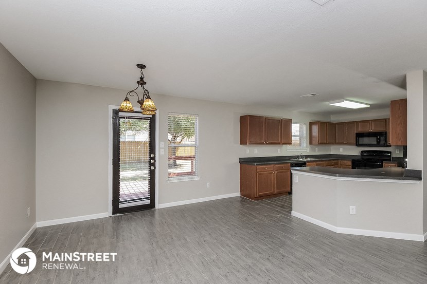 an empty kitchen with wood flooring and a door to a patio