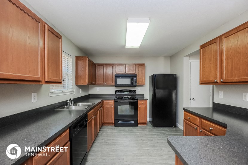 a kitchen with wood cabinets and black counters and black appliances
