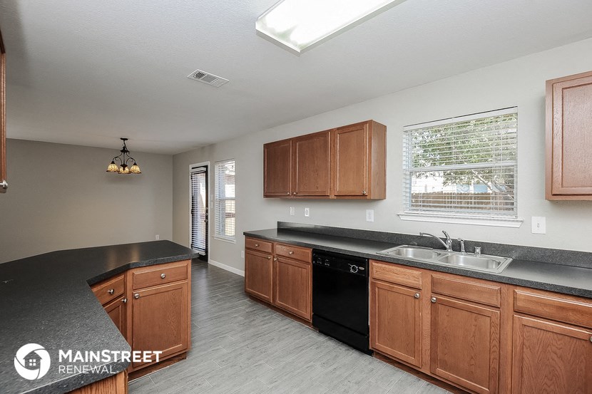 a kitchen with wooden cabinets and black counter tops and a sink