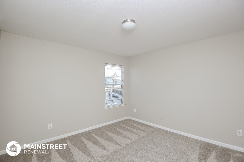 the living room of an apartment with carpet and a window