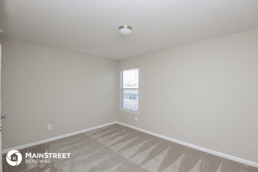 the living room of an apartment with carpet and a window