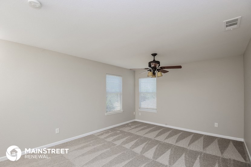 the spacious living room with ceiling fan and carpet