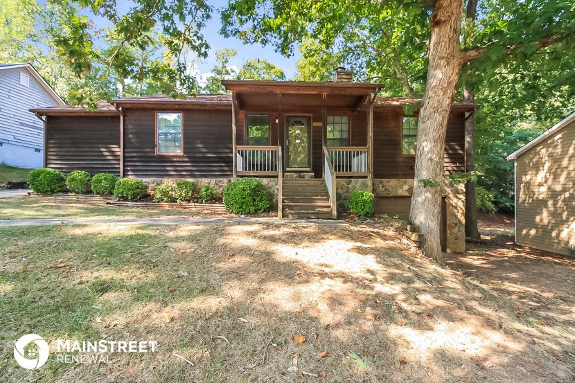 the front of a brown house with a yard and trees