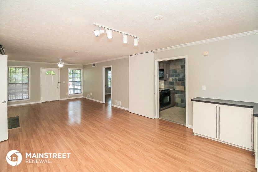 the living room and dining room with wood flooring and white walls
