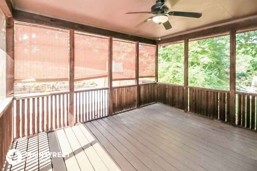 a covered porch with wood floors and a ceiling fan