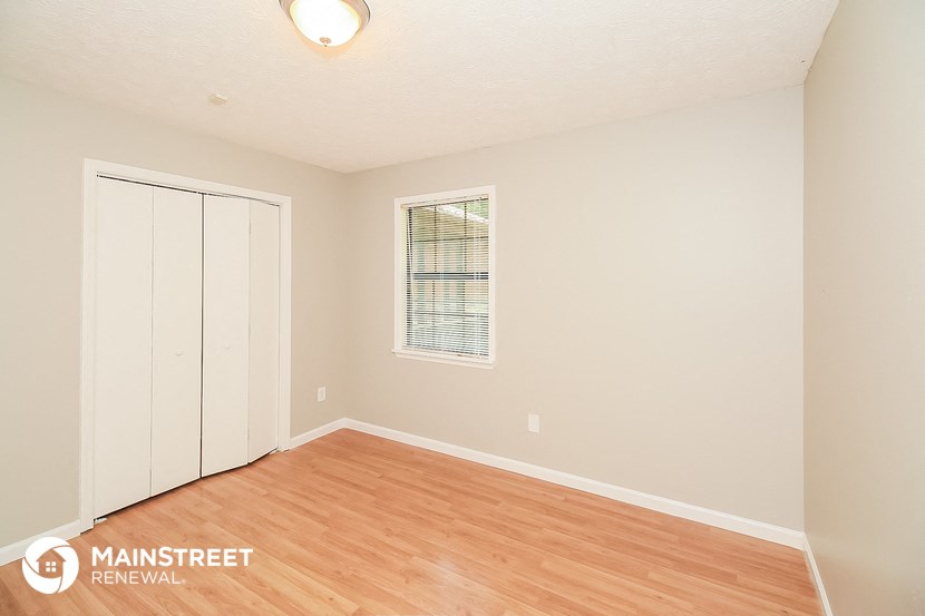 the spacious living room with wood flooring and white walls