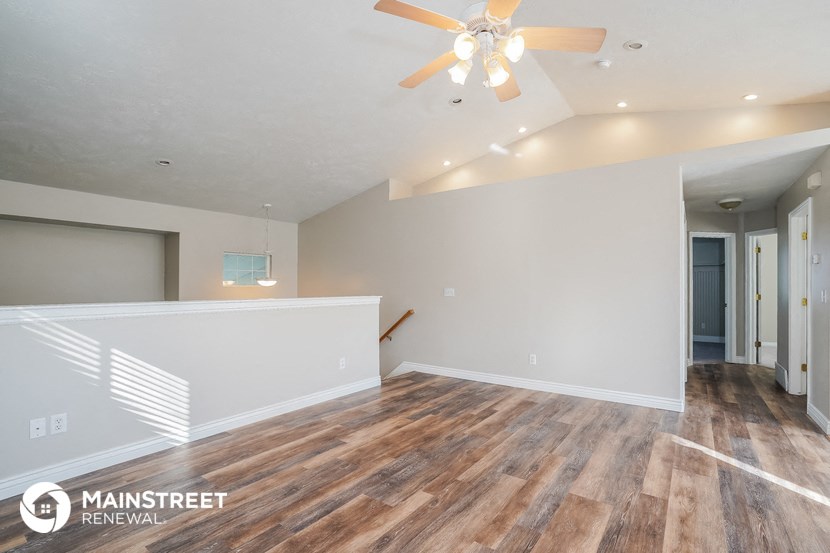 the living room and dining room with wood flooring and a ceiling fan