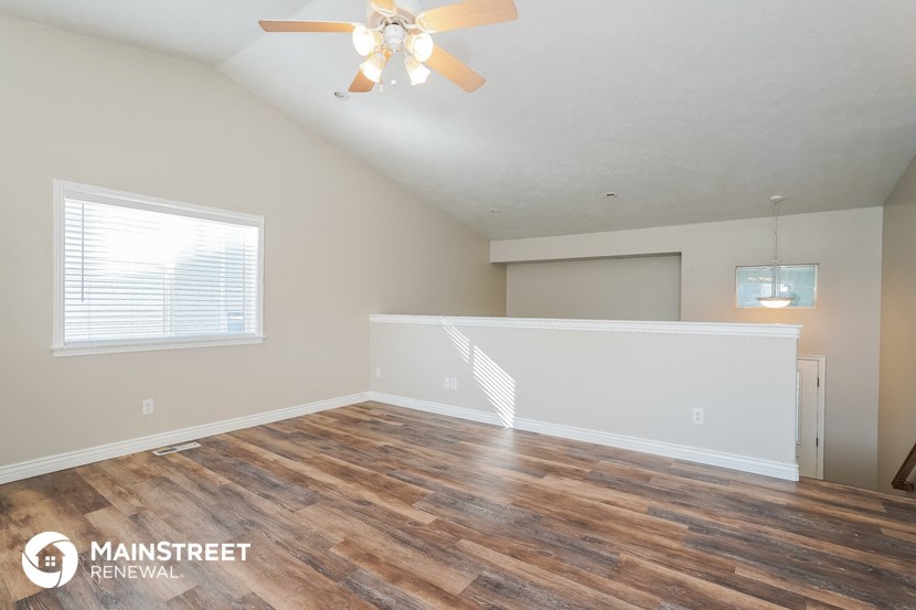 the living room and dining room with wood flooring and a ceiling fan