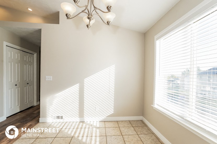 a dining room with a large window and a door to a hallway