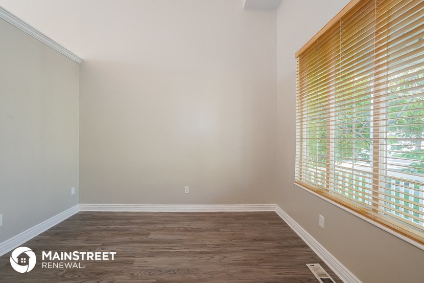 an empty room with wood flooring and a large window