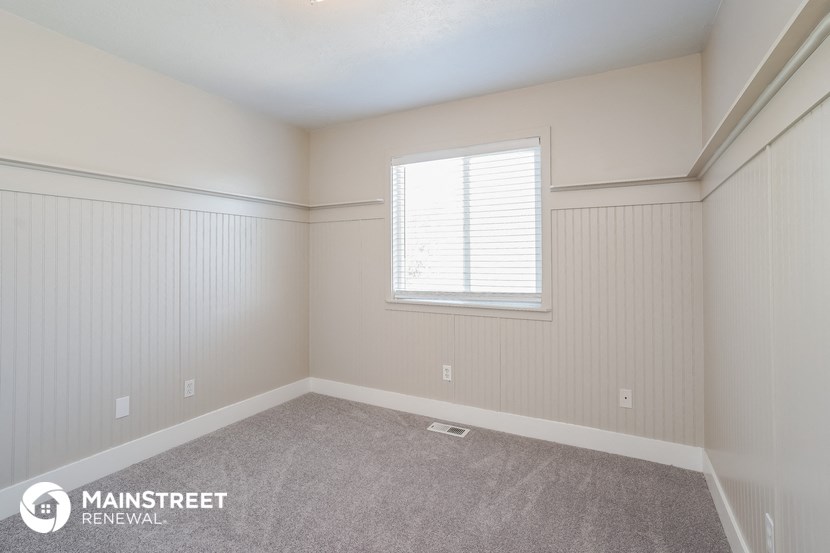 a bedroom with white walls and carpet and a window