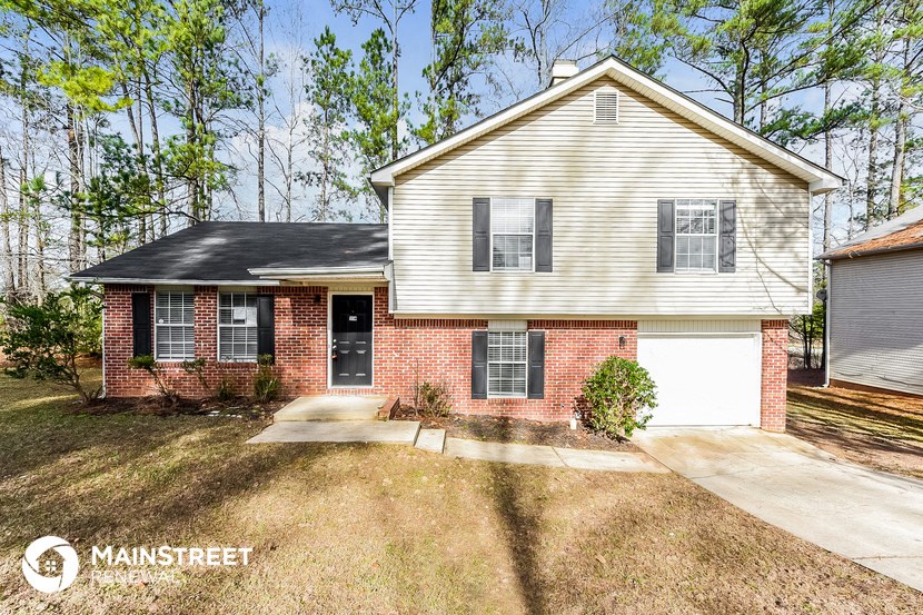 a brick and with a white garage and trees