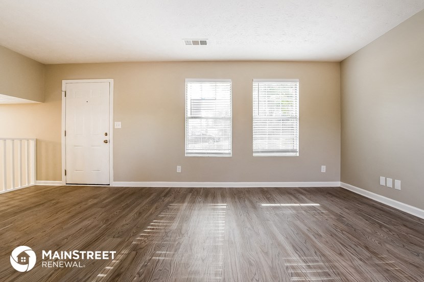 the spacious living room with wood flooring and a white door