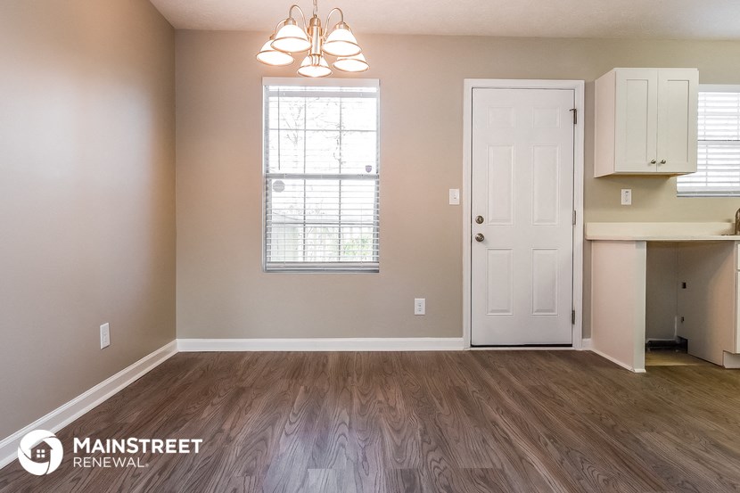 the living room of an apartment with wood flooring and a white door